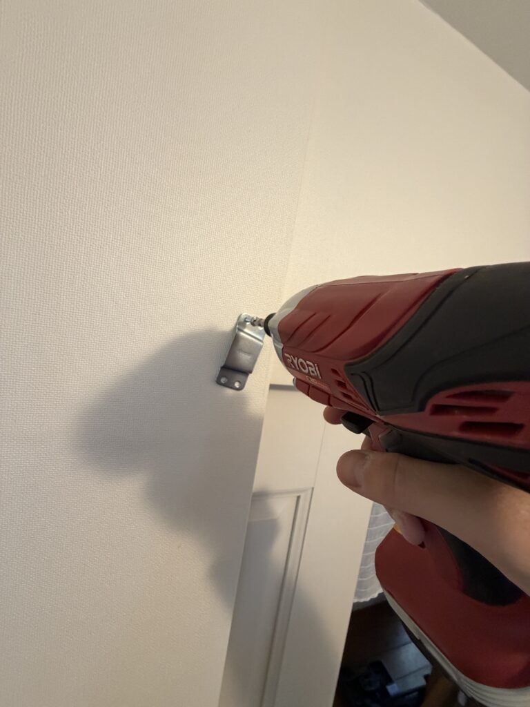 電動工具で金具のネジを留めている写真